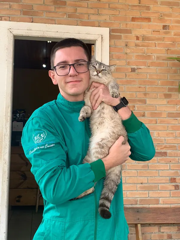 Dr. Octávio Kavalieris de uniforme verde, sorrindo com um gato no colo
